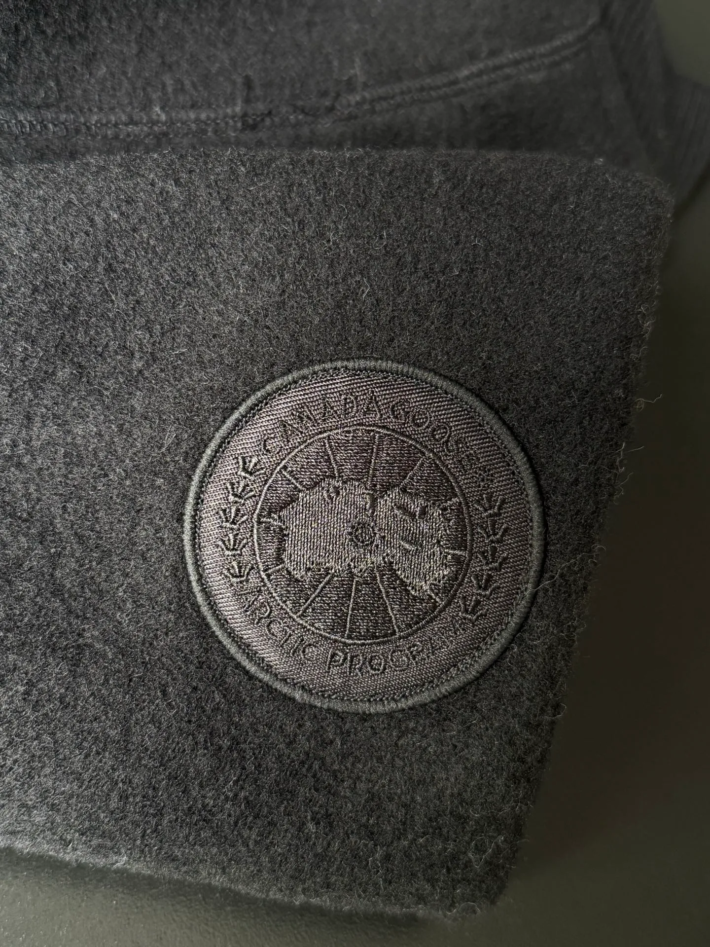 P620 Canada Goose Fleece Wool Baseball Jacket Fabric selection: Wool fleece fabric blended with wool as the main body and a very small amount of spandex and polyester fiber. Wool is a core natural ingredient that provides unparalleled temperature regulation, antibacterial and anti-odor properties and a skin-friendly feel. The feeding of a small amount of spandex gives the fabric a certain degree of four-way elasticity, making it non-restrictive during daily activities. As the basis of fleece's structure, polyester fiber enhances the fabric's durability, wrinkle resistance and quick-drying properties. It contributes to the loft of the fleece and provides functions such as trapping air.  Detail 1: The sleeves and hem are closed with 2×2 ribbing. Its strong elasticity can closely fit wrists and waists of different thicknesses, forming an effective 'seal' to prevent cold wind from blowing back. It can still maintain its original shape after repeated stretching and use, and is not easy to loose and deform. And the ribbed cuffs can convey a sense of design and enhance the visual beauty.  Detail 2: The combination of hood design and elastic buckle improves warmth and windproof performance when wearing. Accessories: Customized elastic drawstring, elastic buckle, custom zipper pendant, custom armband Size: S M L Color: Black Gray Mickey